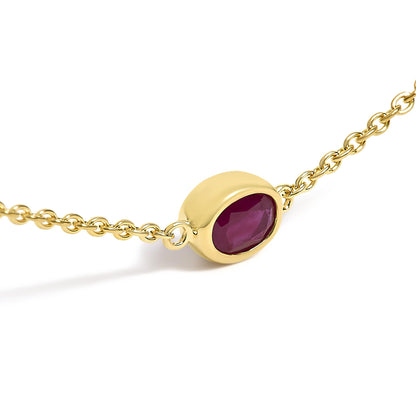 Close-up angled view of a yellow necklace chain featuring an oval red gemstone in a bezel setting.