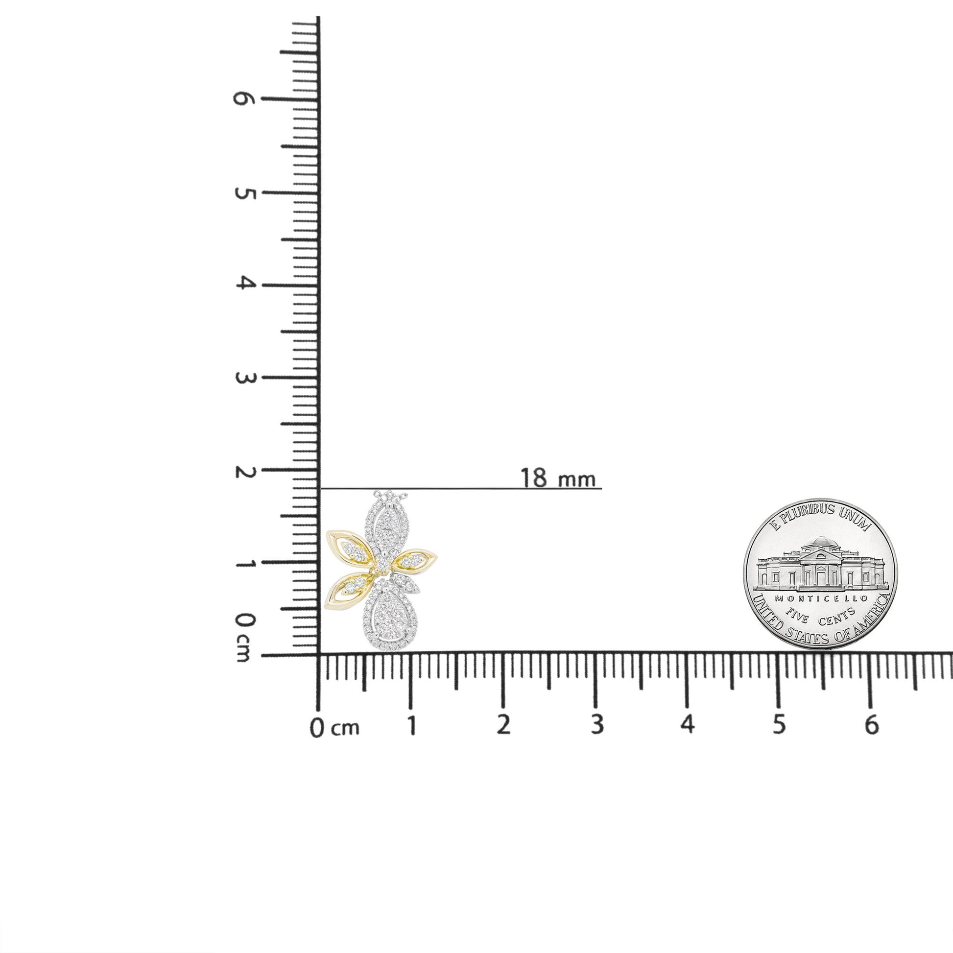 Close-up of a yellow and white metal butterfly-shaped necklace pendant with white round gemstones in prong settings, displayed on a ruler and next to a coin for size reference, shot from the front.
