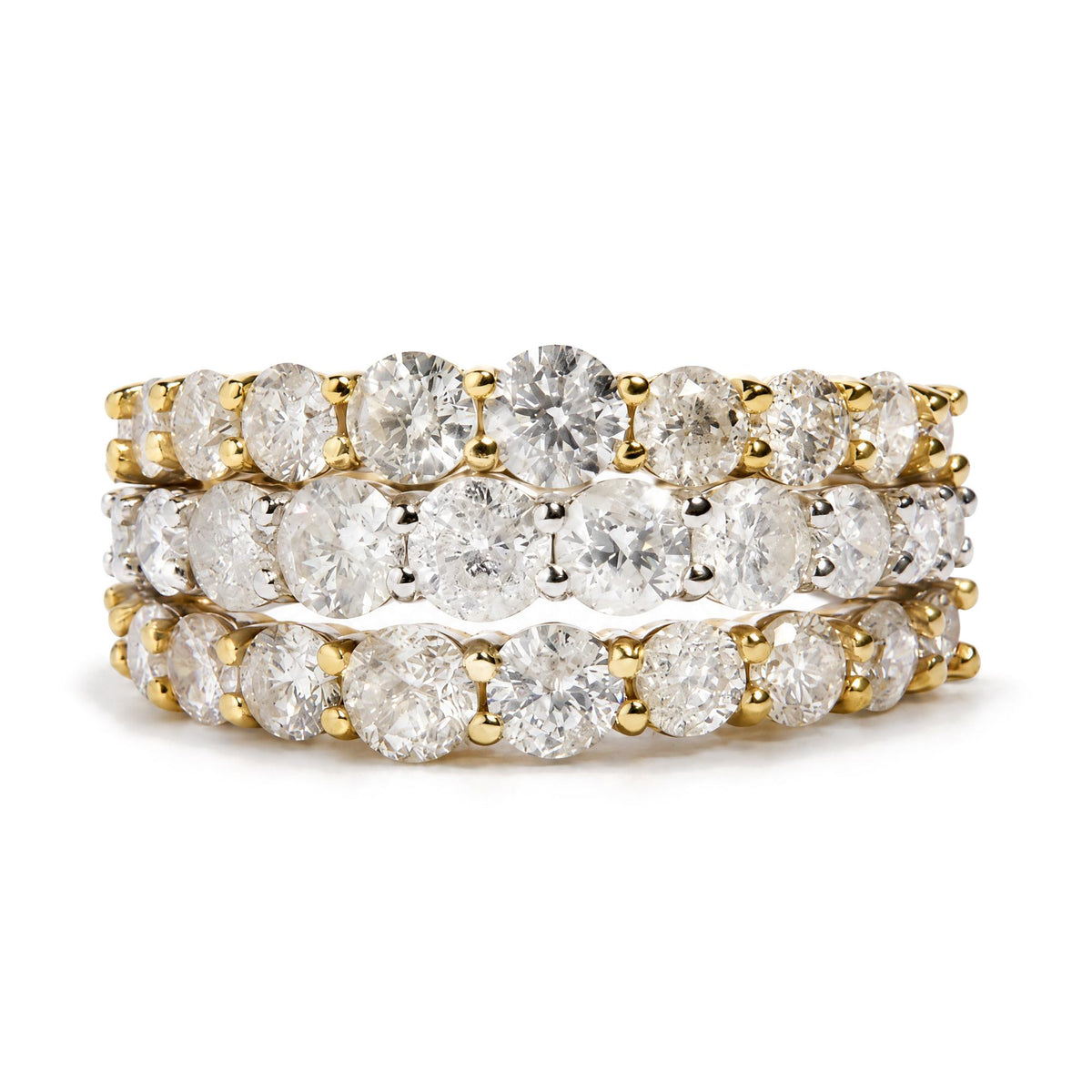 Close-up front angle of three stacked rings with yellow and white metal bands, each set with round white gemstones in a prong setting. Rings are shown on a reflective surface.