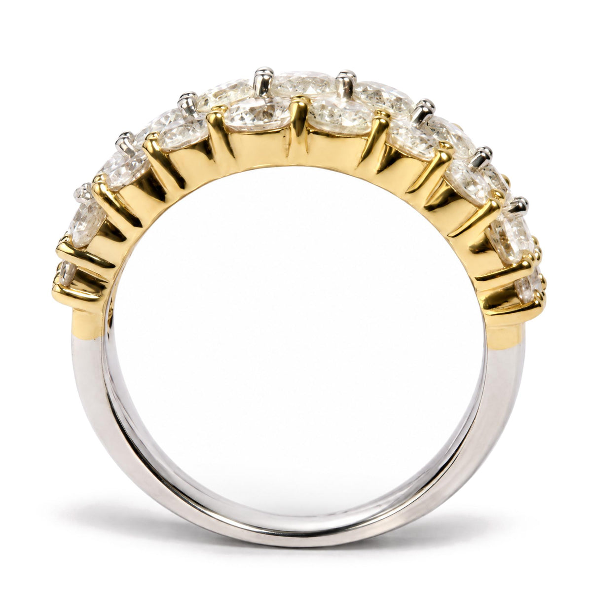Close-up image of a two-tone ring with a yellow upper band featuring round white gemstones in prong settings, and a white lower band, shot from a side angle.