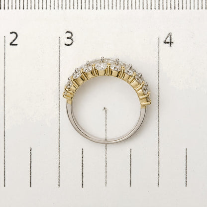 Close-up of a two-tone ring with alternating yellow and white metal bands, set with round white gemstones in prong settings, shown from a top-down angle on a measuring scale.