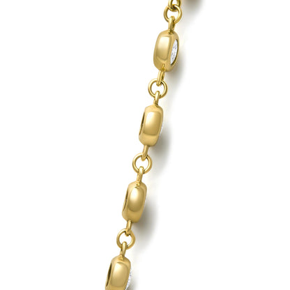 Close-up shot of a yellow metal necklace chain featuring oval-shaped links with round white gemstones set in bezel settings.