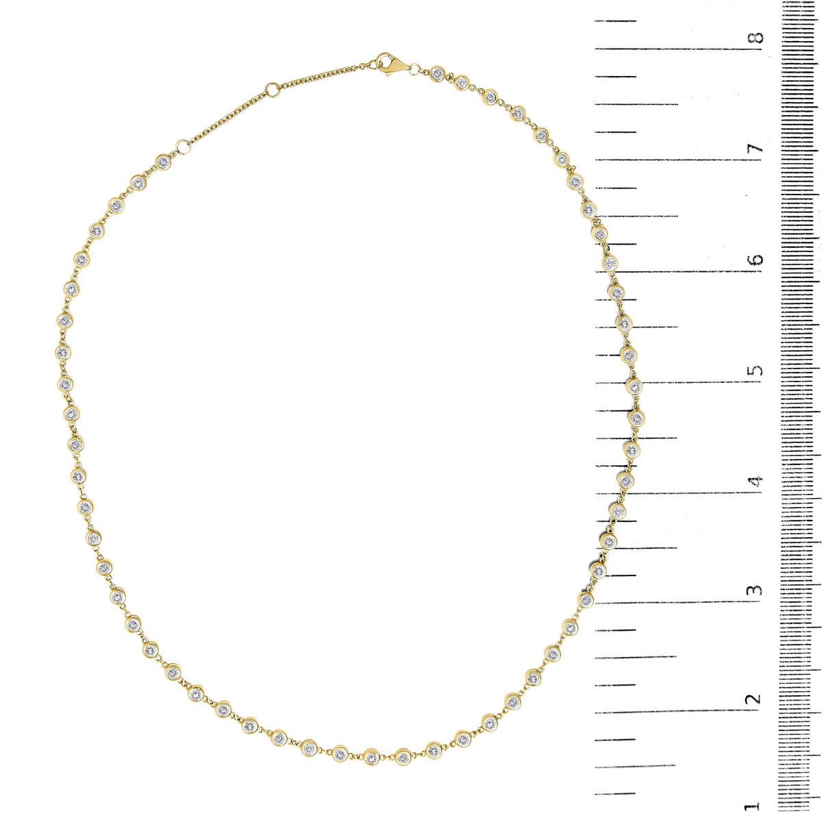 Close-up top-down view of a yellow necklace with round white gemstones in bezel settings, shown on a scale.