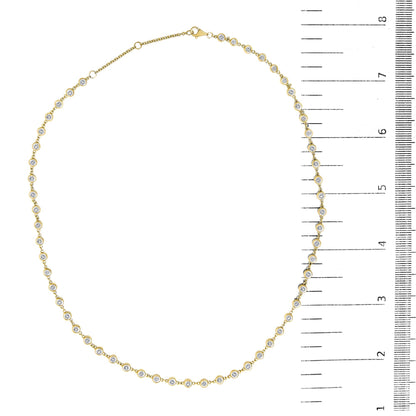 Close-up top-down view of a yellow necklace with round white gemstones in bezel settings, shown on a scale.