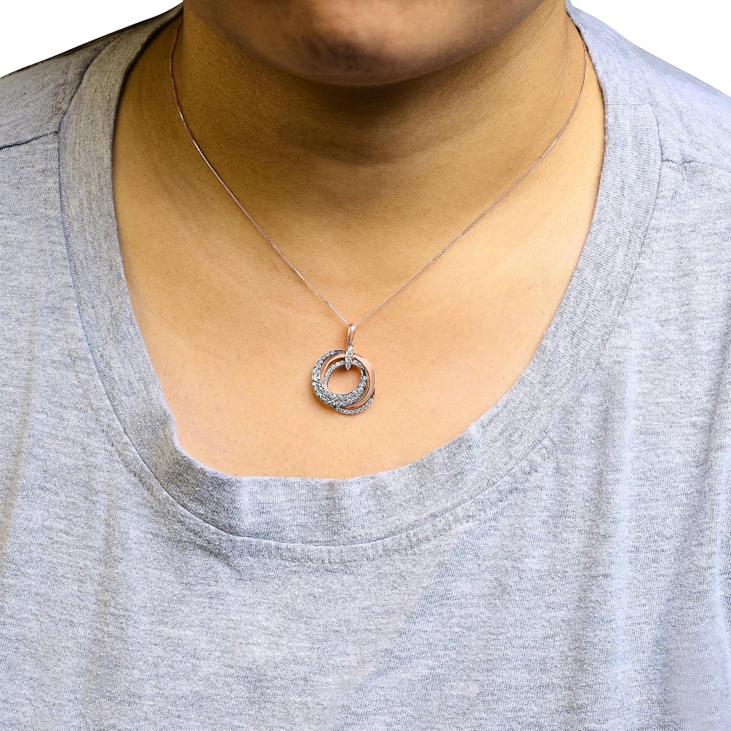 Rose metal necklace with two interlocking circular pendants, one partially covered with white and brown pave-set round gemstones, shown on a model from the front.