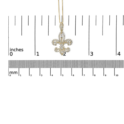 Front view of a yellow metal necklace pendant with white round gemstones in prong settings, shaped like a fleur-de-lis, displayed on a ruler for size reference.