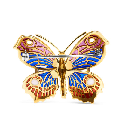 Back view of yellow metal butterfly brooch with pink, blue, red, and white enamel accents, shown against a white background.