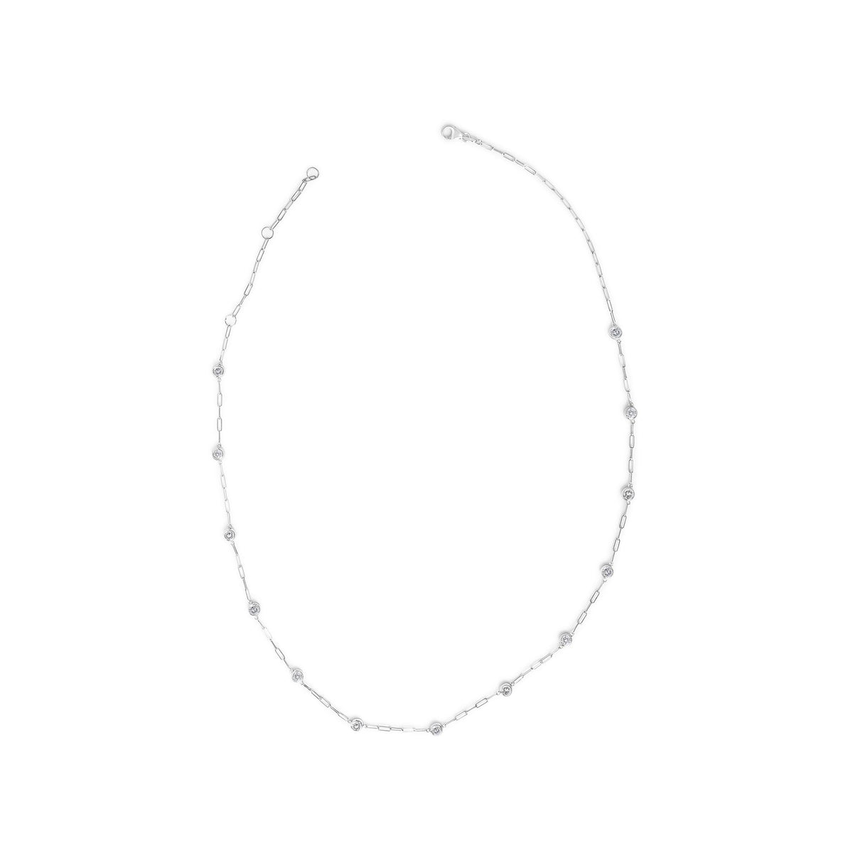 White metal necklace shown on a scale, laid flat in a circular shape with evenly spaced bezel-set round white gemstones along delicate chain links, photographed from above.