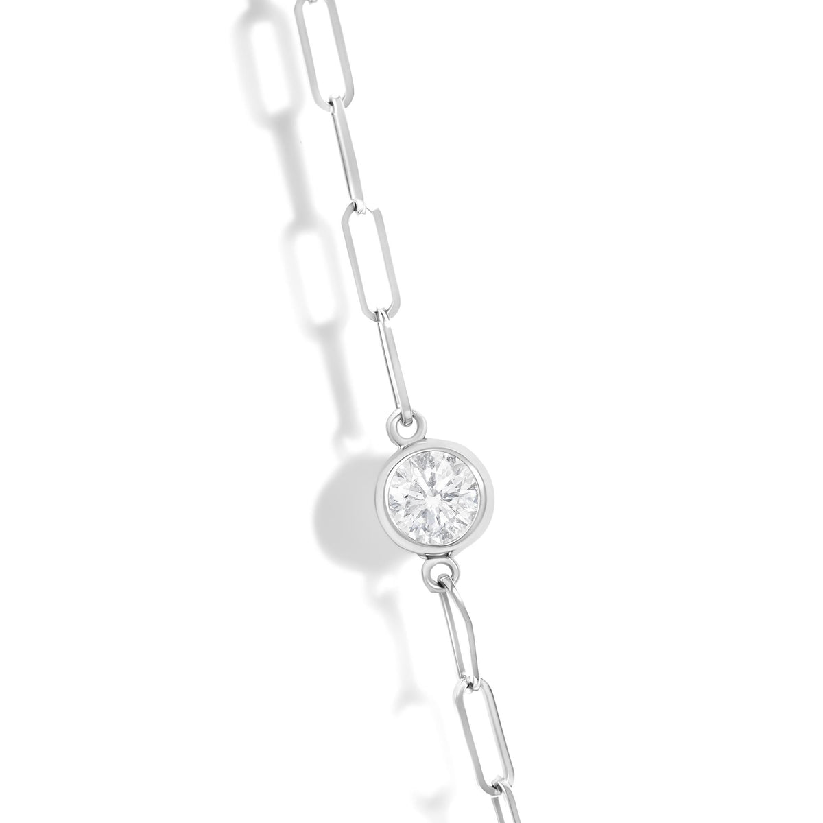 Close-up front angle of a white metal necklace chain with a round bezel-set white gemstone pendant, shown on a white background.