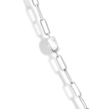 Close-up angled view of a white metal necklace featuring elongated chain links and a rectangular pendant set with multiple round white gemstones in bezel settings.