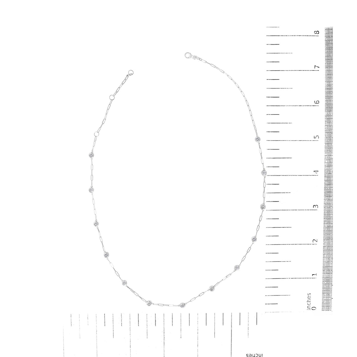 White metal necklace with round white gemstones in bezel settings along a linked chain, shown from a top-down angle on a ruler scale.