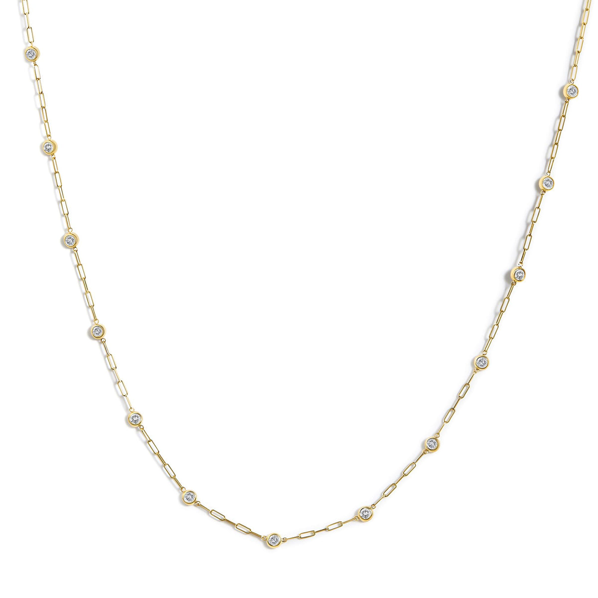 Yellow metal necklace with linked chain and round white gemstones in bezel settings, shown in a flat lay, close-up angle.