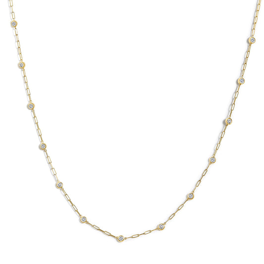 Yellow metal necklace with linked chain and round white gemstones in bezel settings, shown in a flat lay, close-up angle.
