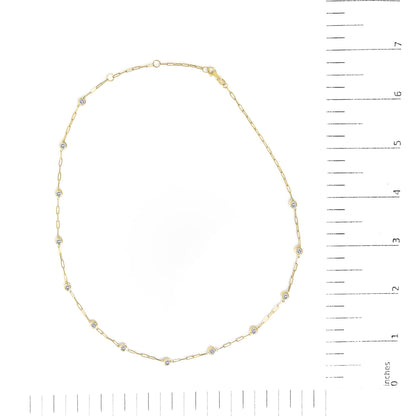Yellow necklace with small bezel set round white gemstones linked by thin chain, shown flat on a scale from above.
