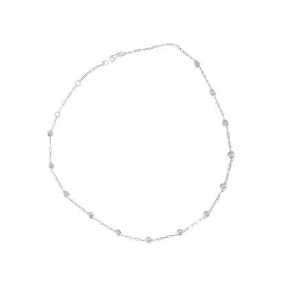 Close-up image of a white necklace laid flat, featuring a chain with evenly spaced round white gemstones in bezel settings, shot from above.