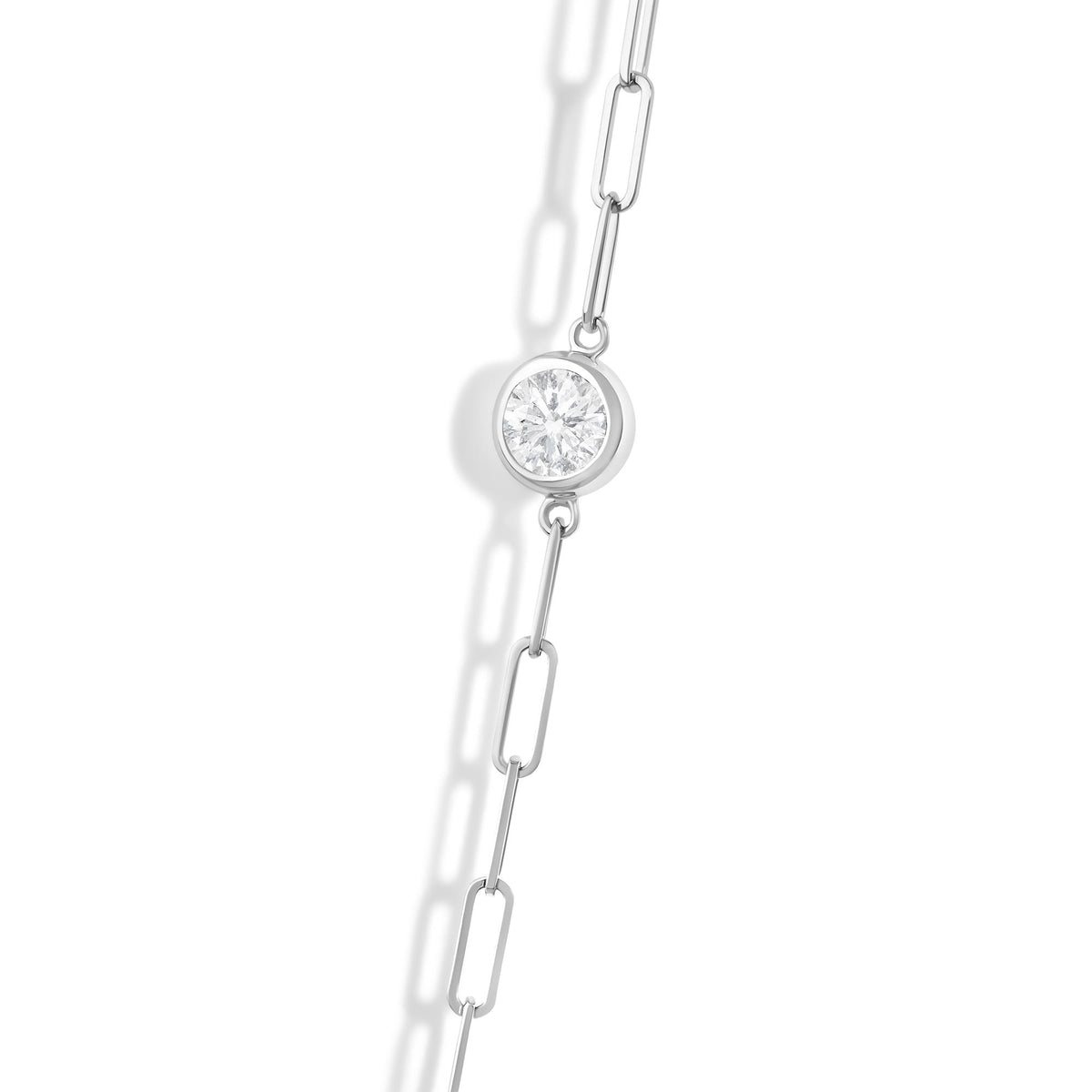 Close-up angled view of a white metal necklace chain featuring a round white gemstone in a bezel setting.