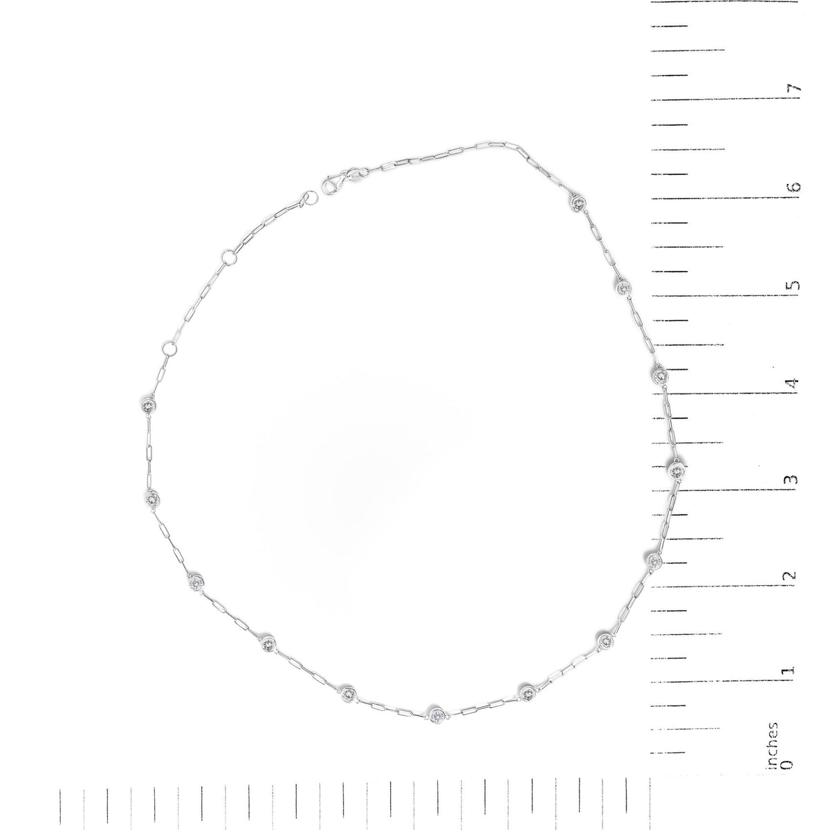 White necklace with round white gemstones in bezel settings spaced along a delicate chain, shown flat on a scale, top-down view.