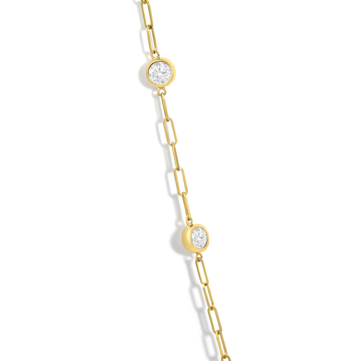 Close-up angled view of a yellow necklace chain with round white gemstones set in bezel settings along the chain.