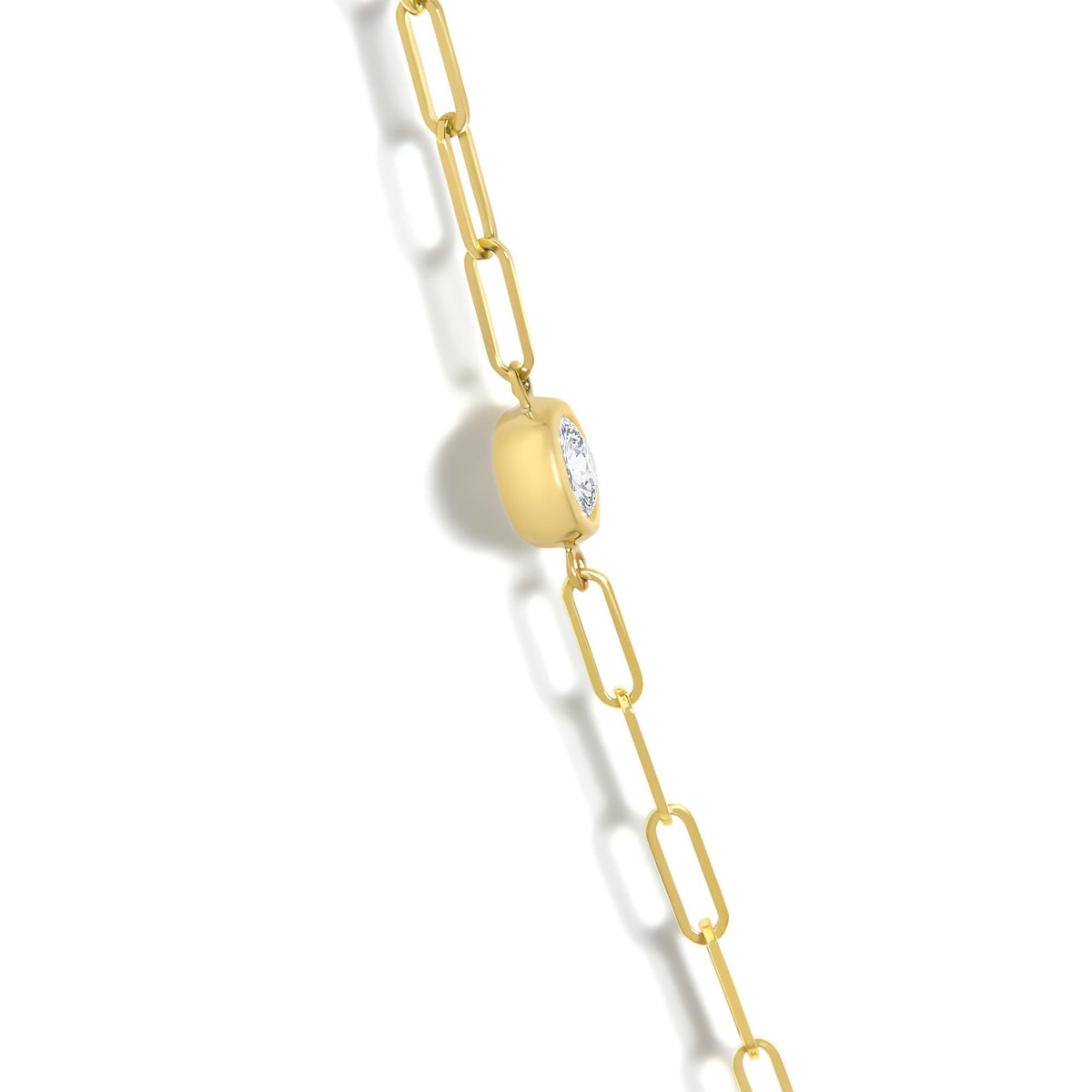 Close-up angled view of a yellow necklace with oblong chain links and a rounded square pendant featuring a round white gemstone in bezel setting.