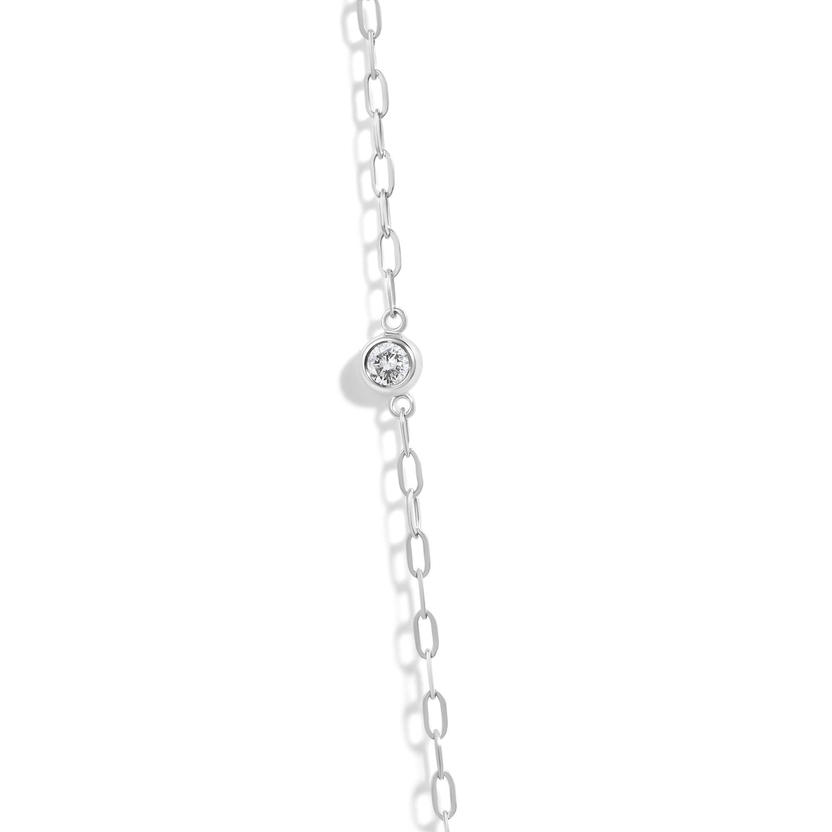 Close-up front angle of a white necklace chain with a bezel-set round white gemstone pendant, shown on a white background.