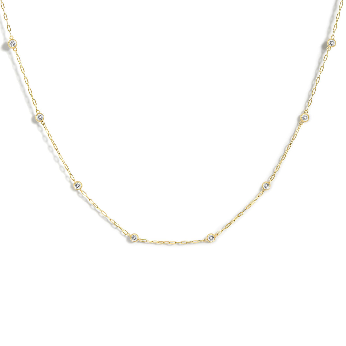 Close-up front angle of a yellow necklace featuring round white gemstones in bezel settings evenly spaced along a delicate chain, shown on a white background.