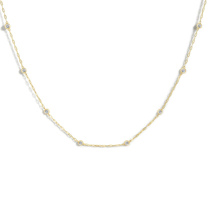 Close-up front angle of a yellow necklace featuring round white gemstones in bezel settings evenly spaced along a delicate chain, shown on a white background.