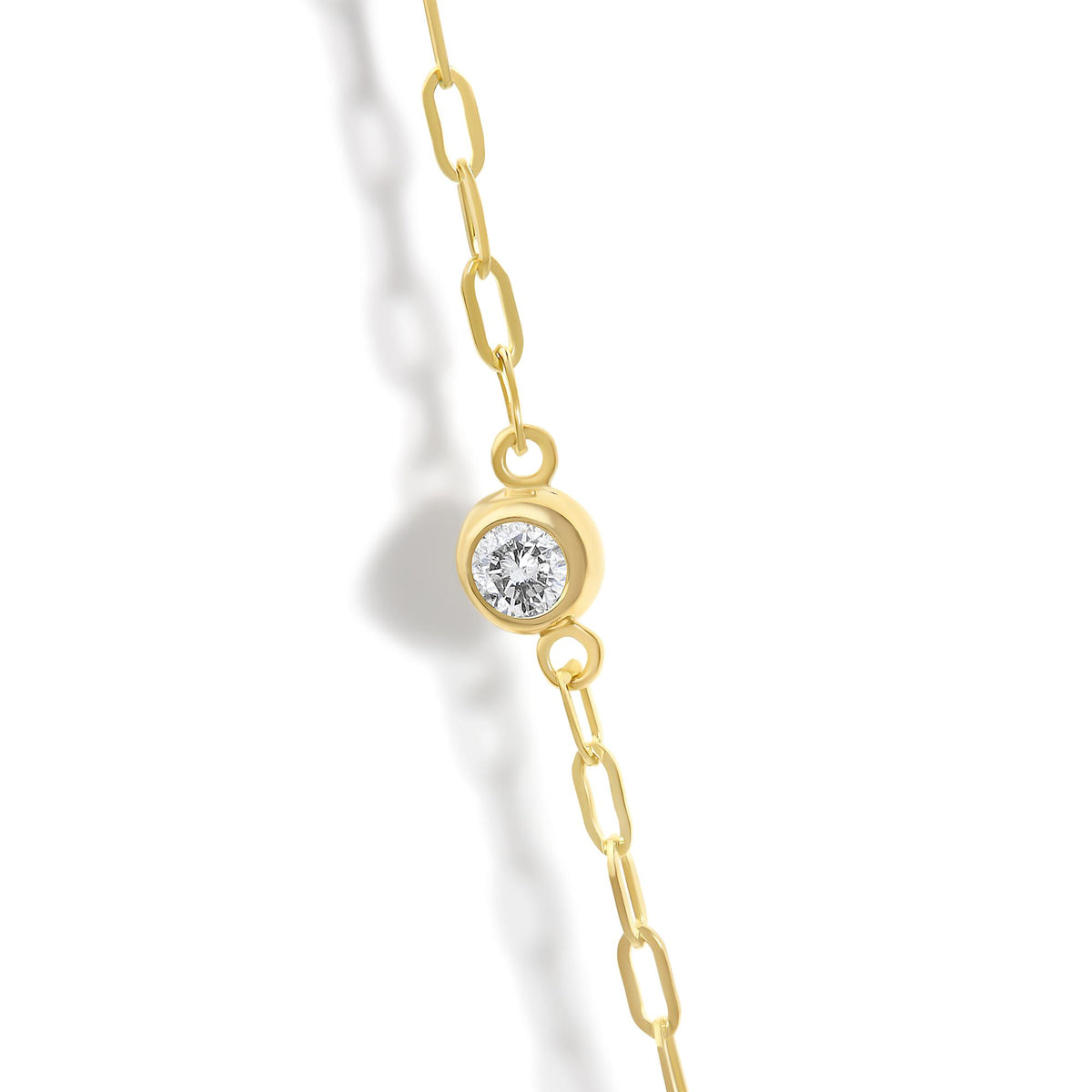 Close-up front angle of a yellow chain necklace featuring a round white gemstone in a bezel setting.