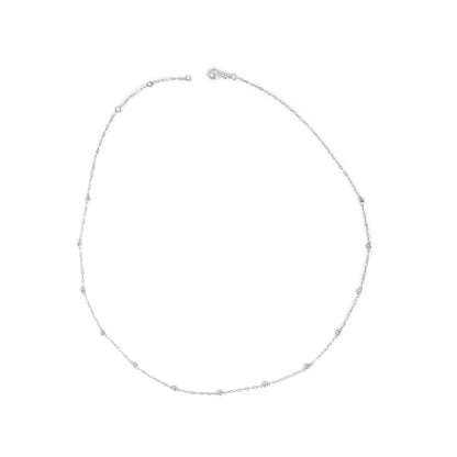 Top-down view of a white metal necklace with round white gemstones in bezel settings spaced along a delicate chain, shown laid flat on a white background.