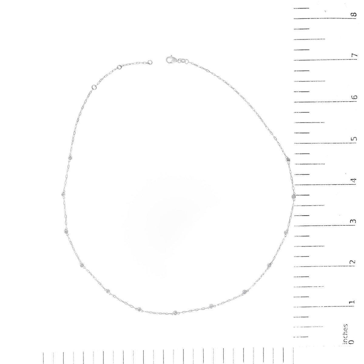 White metal necklace with round white gemstones in bezel settings evenly spaced along a delicate chain, shown flat on a scale with measurement markings, top-down view.