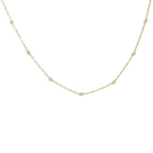 Close-up front angle of a yellow metal necklace featuring round white gemstones in bezel settings spaced evenly along a delicate chain.