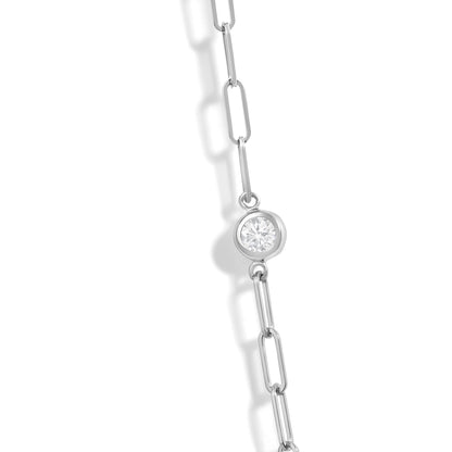 Close-up angled view of a white metal necklace chain with bezel-set round white gemstones.