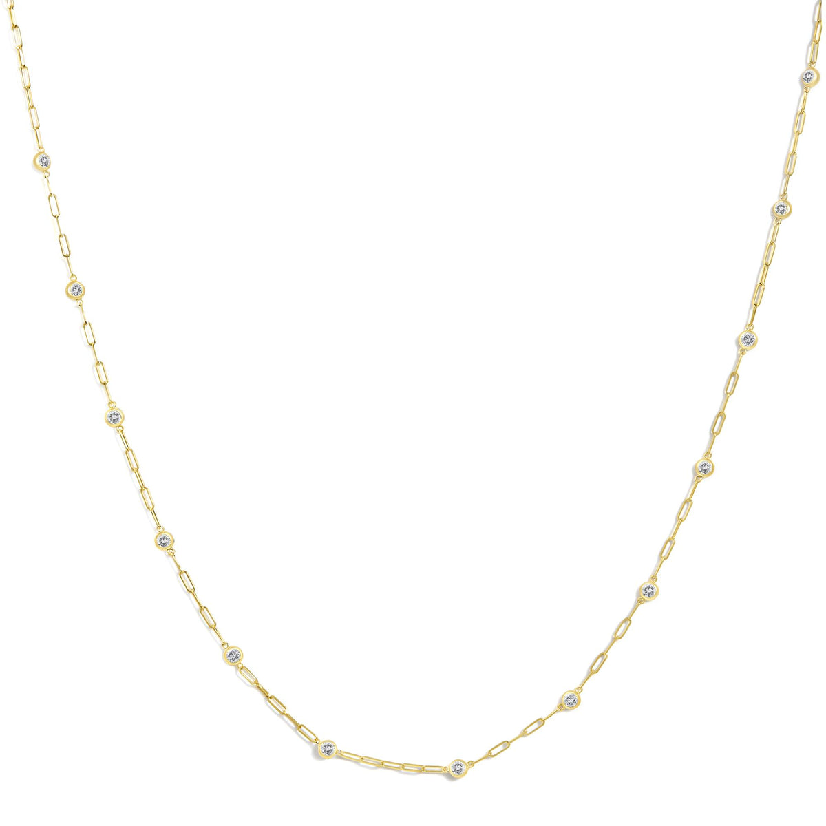 Close-up front angle of a yellow necklace chain with evenly spaced round white gemstones in bezel settings.