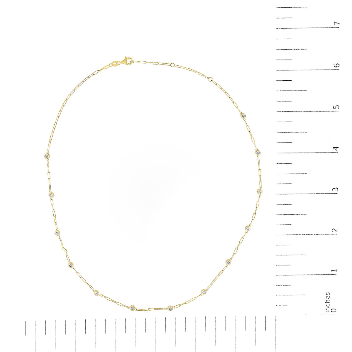 Top view of a yellow necklace with round white gemstones in bezel settings along the chain, shown on a scale.