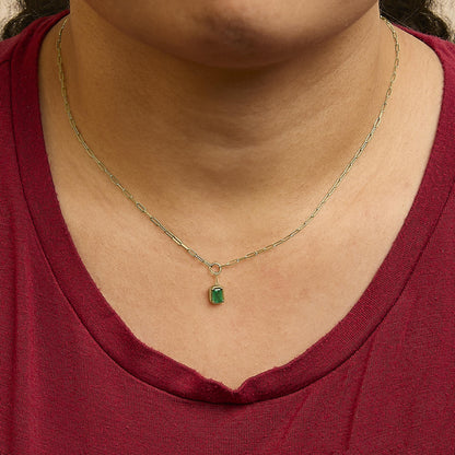 Yellow metal necklace with a rectangular green gemstone pendant in bezel setting, shown worn on a model, close-up front angle.