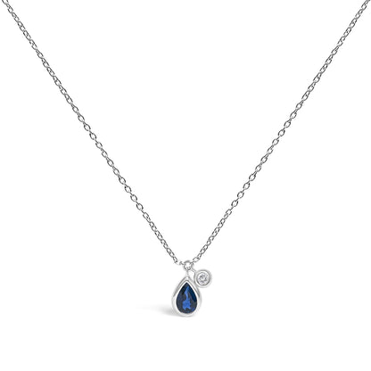 White necklace with pear-shaped blue gemstone and round white gemstone pendants in bezel settings, shown in a centered front-facing view.