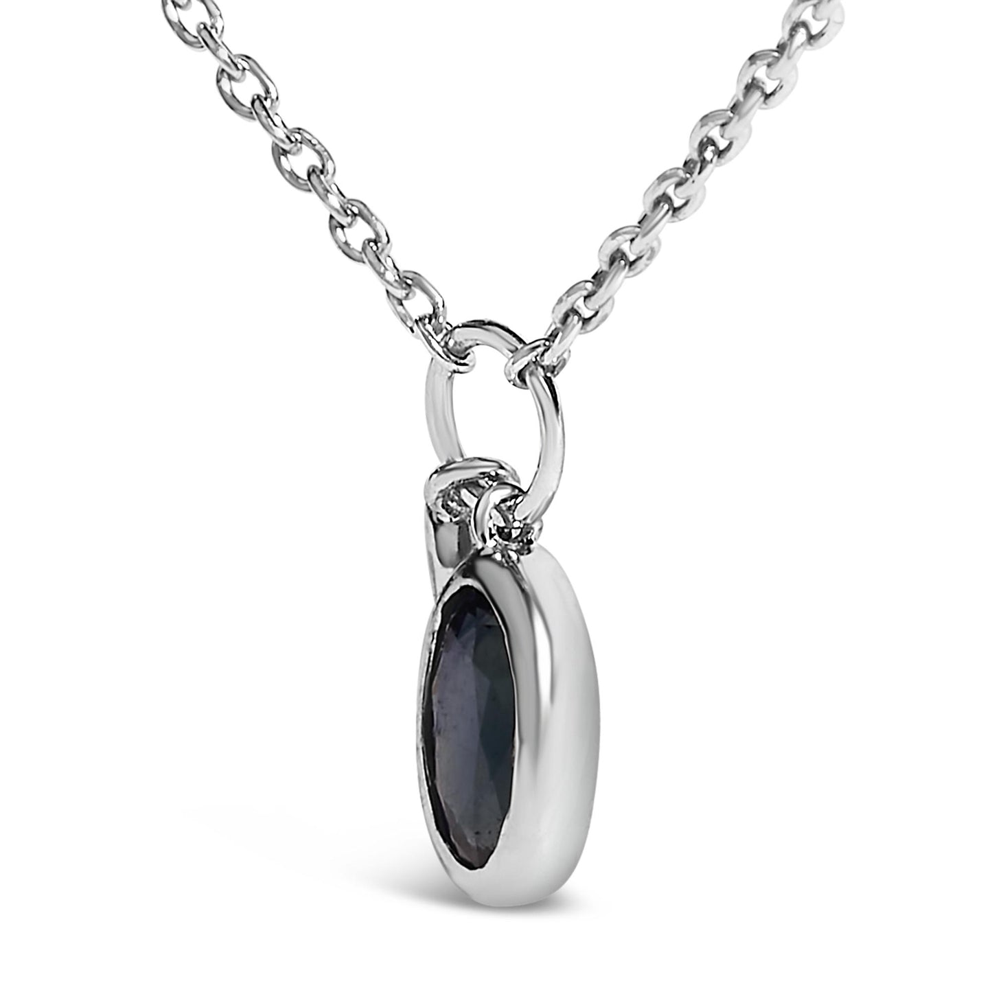 Close-up front angled view of a white metal necklace with a pendant featuring an oval blue gemstone and a small round white gemstone, both bezel set.