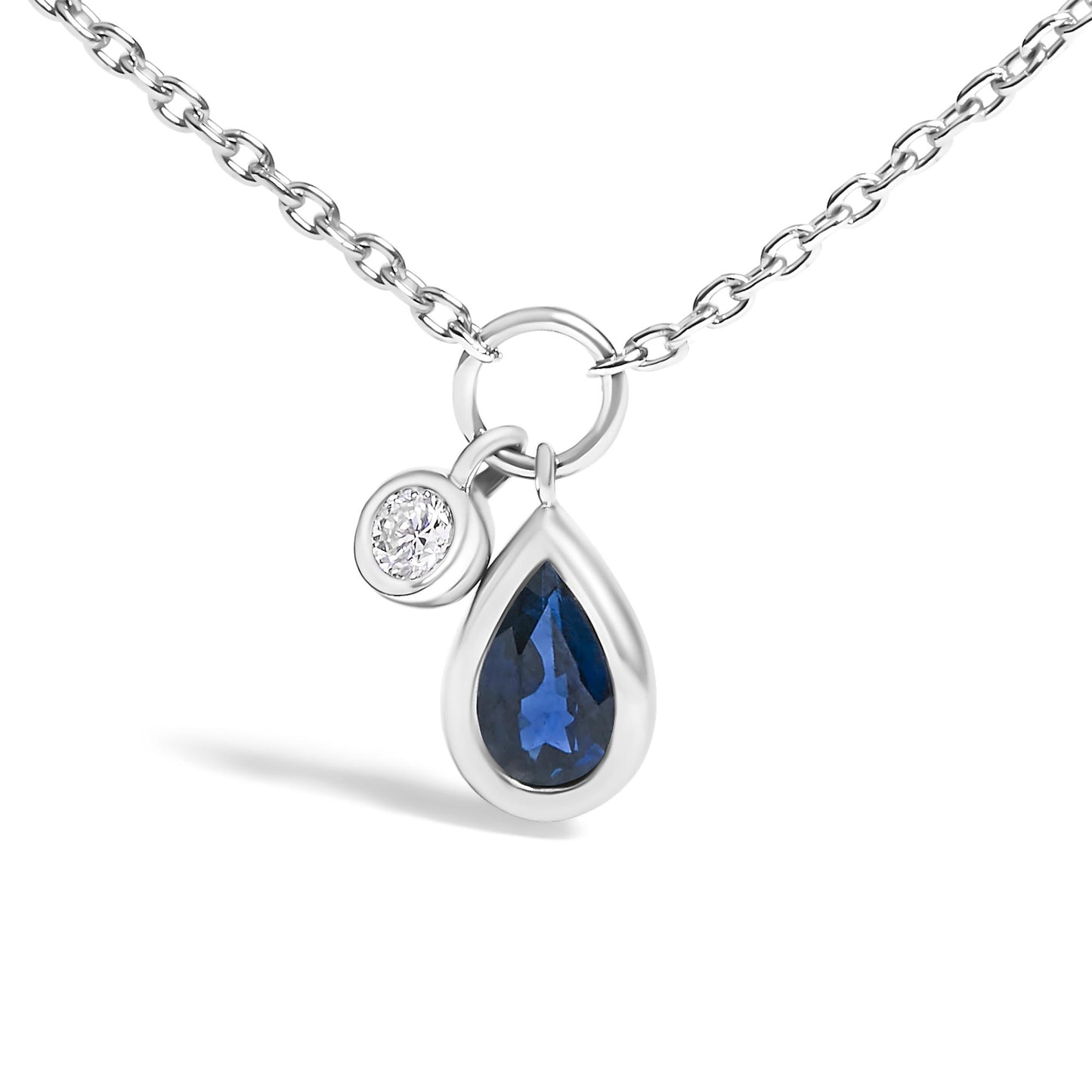 Close-up front angle of a white metal chain necklace with two bezel-set pendants: a round white gemstone and a pear-shaped blue gemstone.