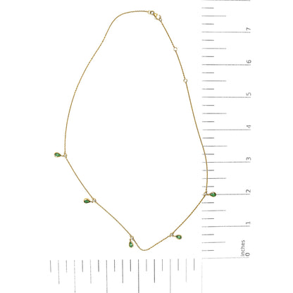 Yellow necklace with small pear-shaped green gemstones and round white gemstones in bezel settings, shown on a ruler scale from a top-down angle.