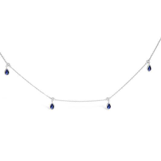 White necklace with a thin chain featuring alternating round white gemstones and pear-shaped blue gemstones in bezel settings, shown on a white background angle.