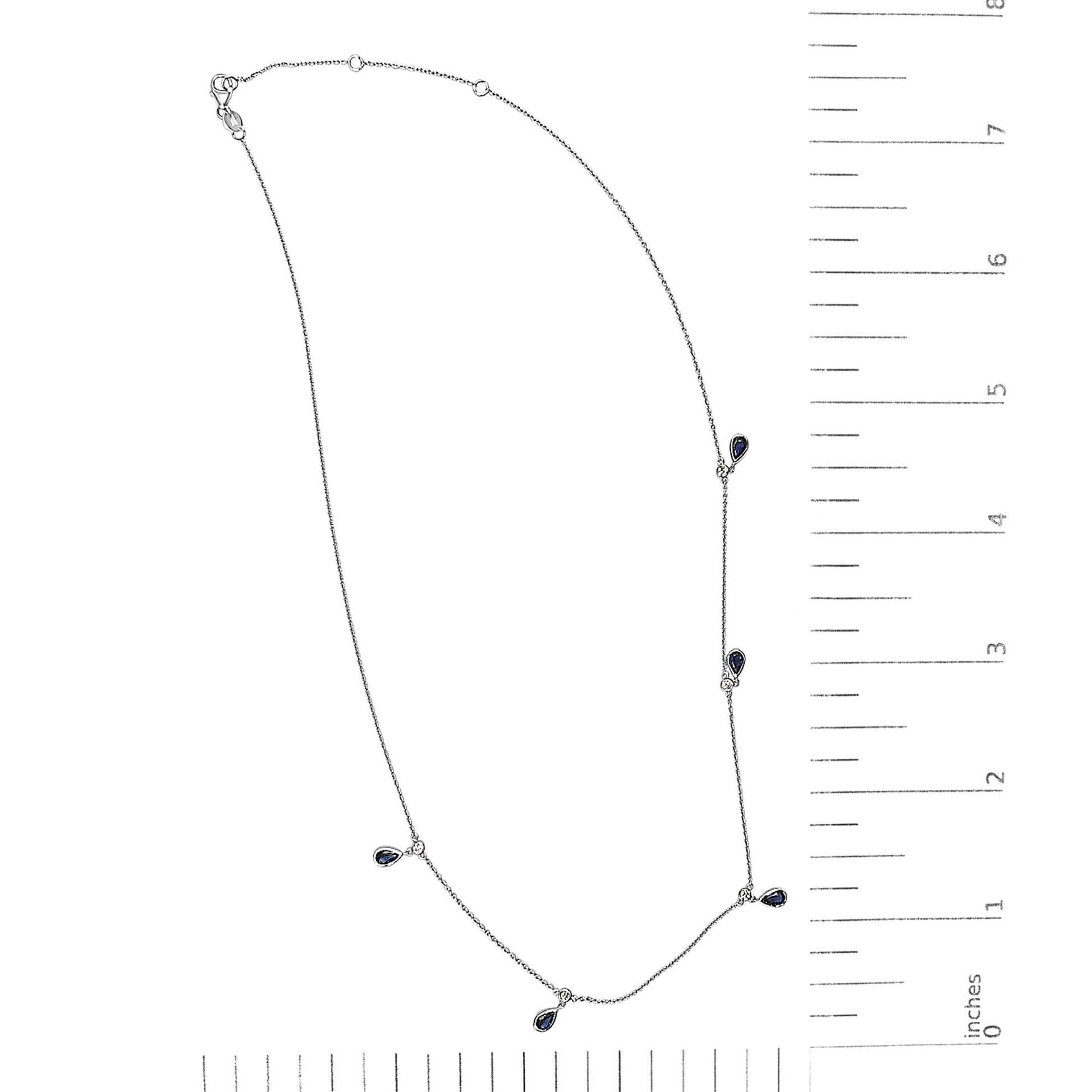 White necklace with small round white gemstones and pear-shaped blue gemstones in bezel settings, shown on a scale, top-down view.