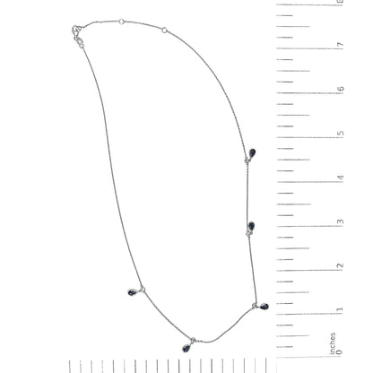 White necklace with small round white gemstones and pear-shaped blue gemstones in bezel settings, shown on a scale, top-down view.