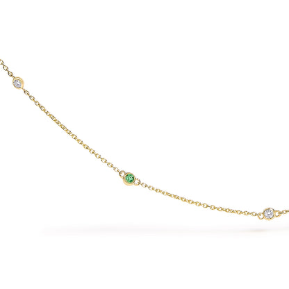 Close-up front view of a yellow metal necklace chain with round bezel-set white and green gemstones spaced along the chain.