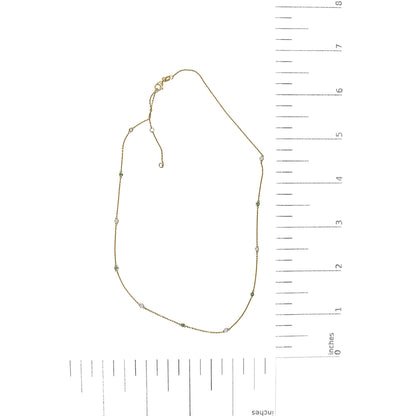 Yellow metal necklace shown flat on a scale with round white and green gemstones in bezel settings spaced along the chain.