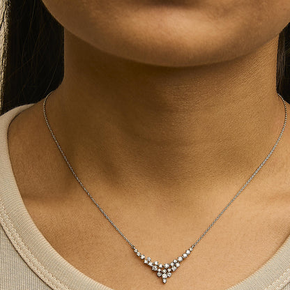 Close-up front view of a yellow metal necklace with a cluster of white round gemstones in prong settings, shown worn on a model.