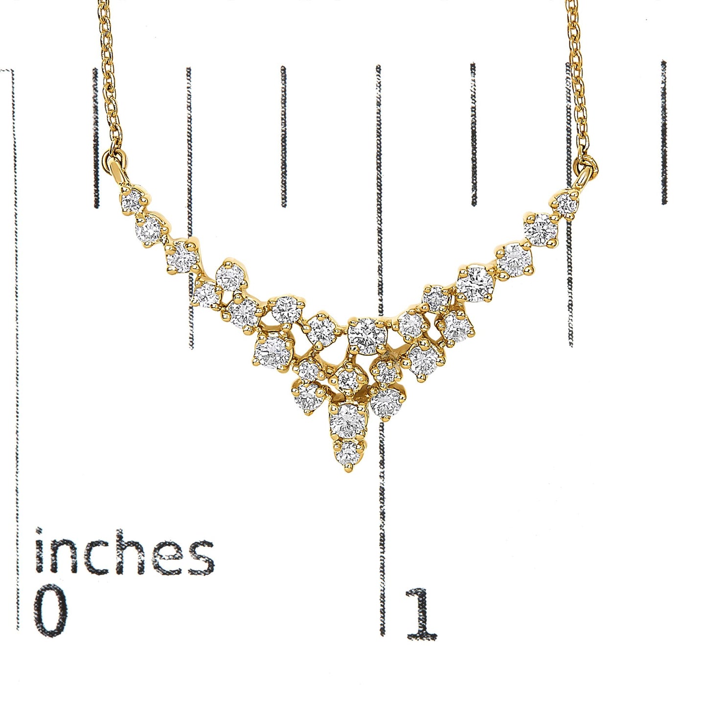 Yellow metal necklace with multiple round white gemstones in prong settings arranged in a cascading design, shown on a scale with inch markings, front-facing angle.