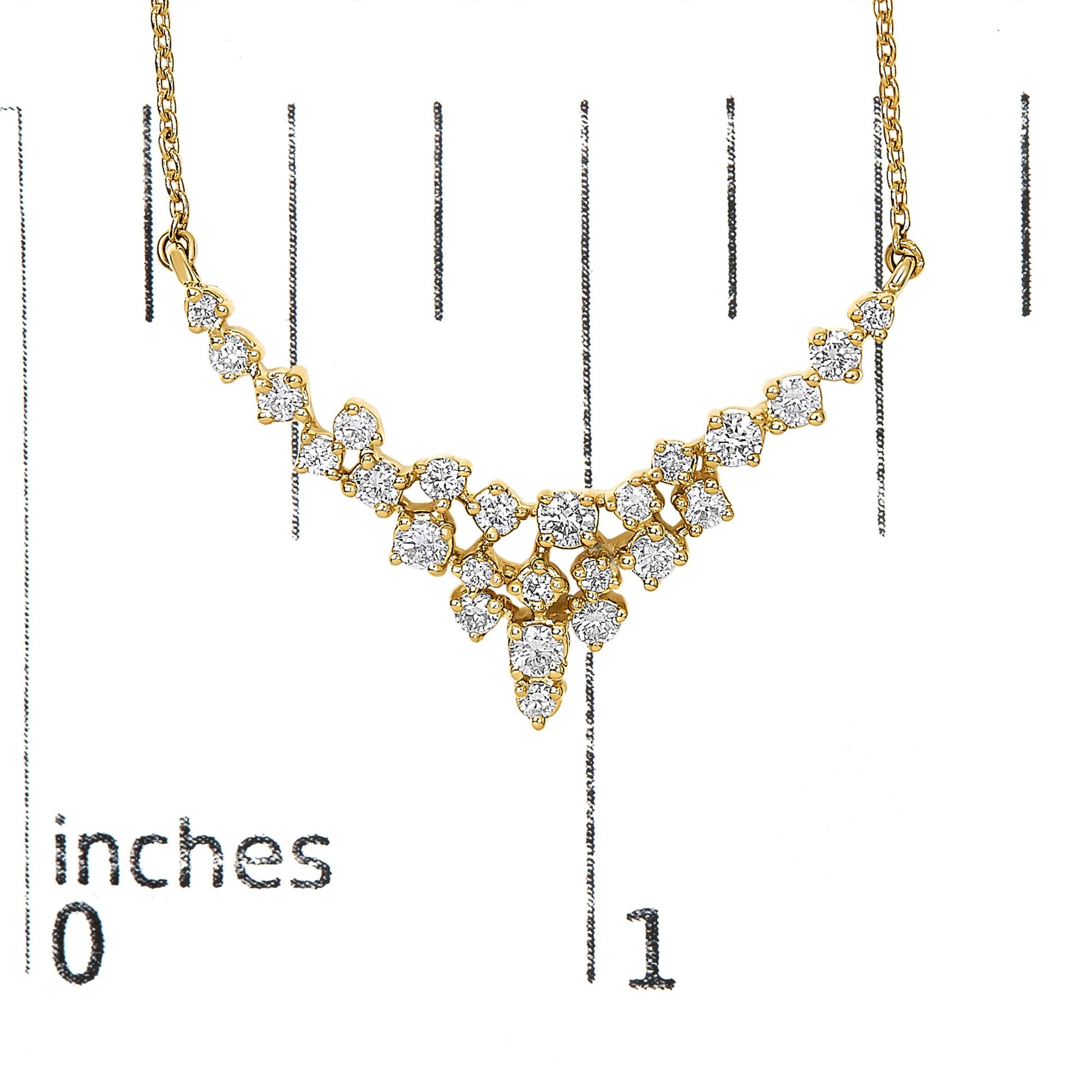 Yellow metal necklace with multiple round white gemstones in prong settings arranged in a cascading design, shown on a scale with inch markings, front-facing angle.