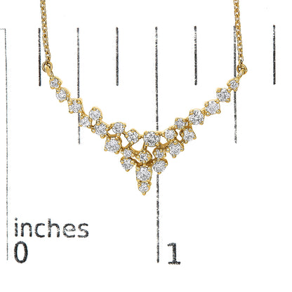 Yellow metal necklace with multiple round white gemstones in prong settings arranged in a cascading design, shown on a scale with inch markings, front-facing angle.