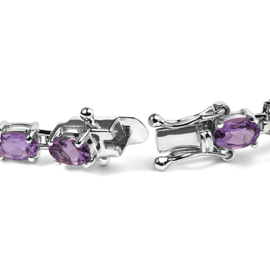 Close-up side angle of an open white metal bracelet featuring oval purple gemstones in four-prong settings.