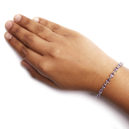 White metal bracelet with oval purple gemstones in 4-prong settings worn on wrist, side angle.