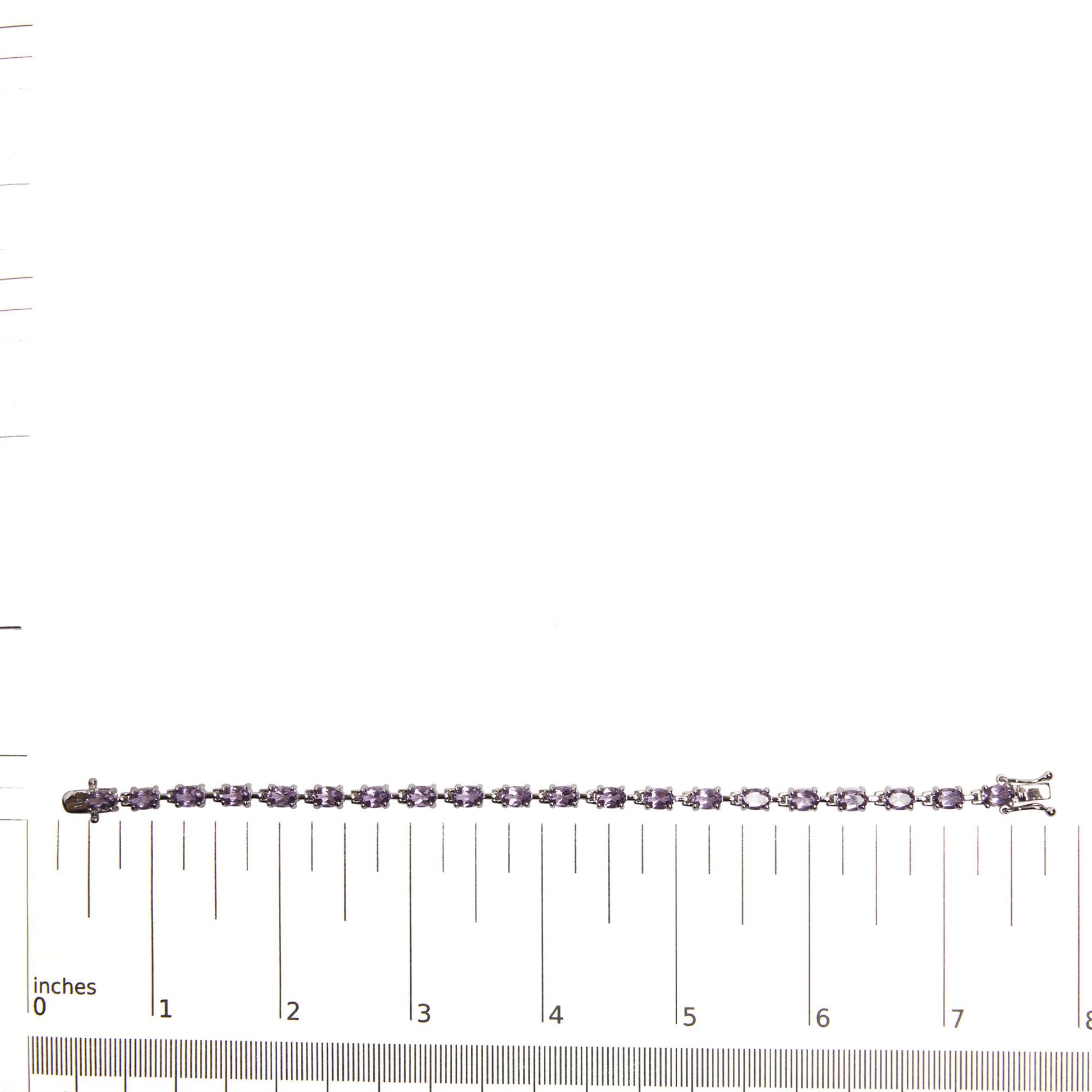 White metal bracelet with purple oval gemstones in 4-prong settings, laid flat on a ruler for size reference, shot from above.